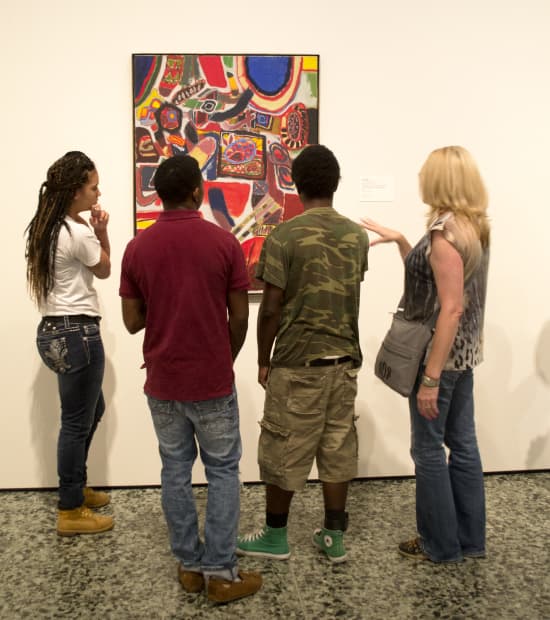 Four people stand looking at an abstract painting