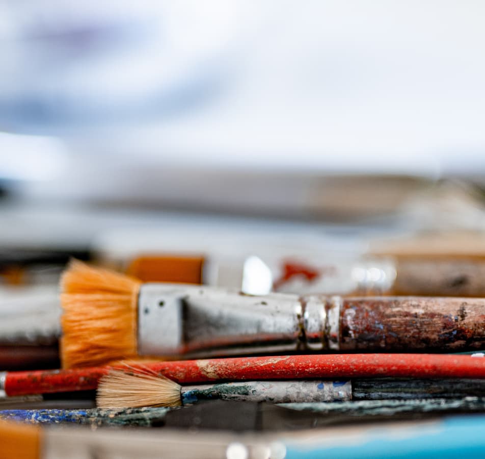 Up close photograph of old paintbrushes laying on a table